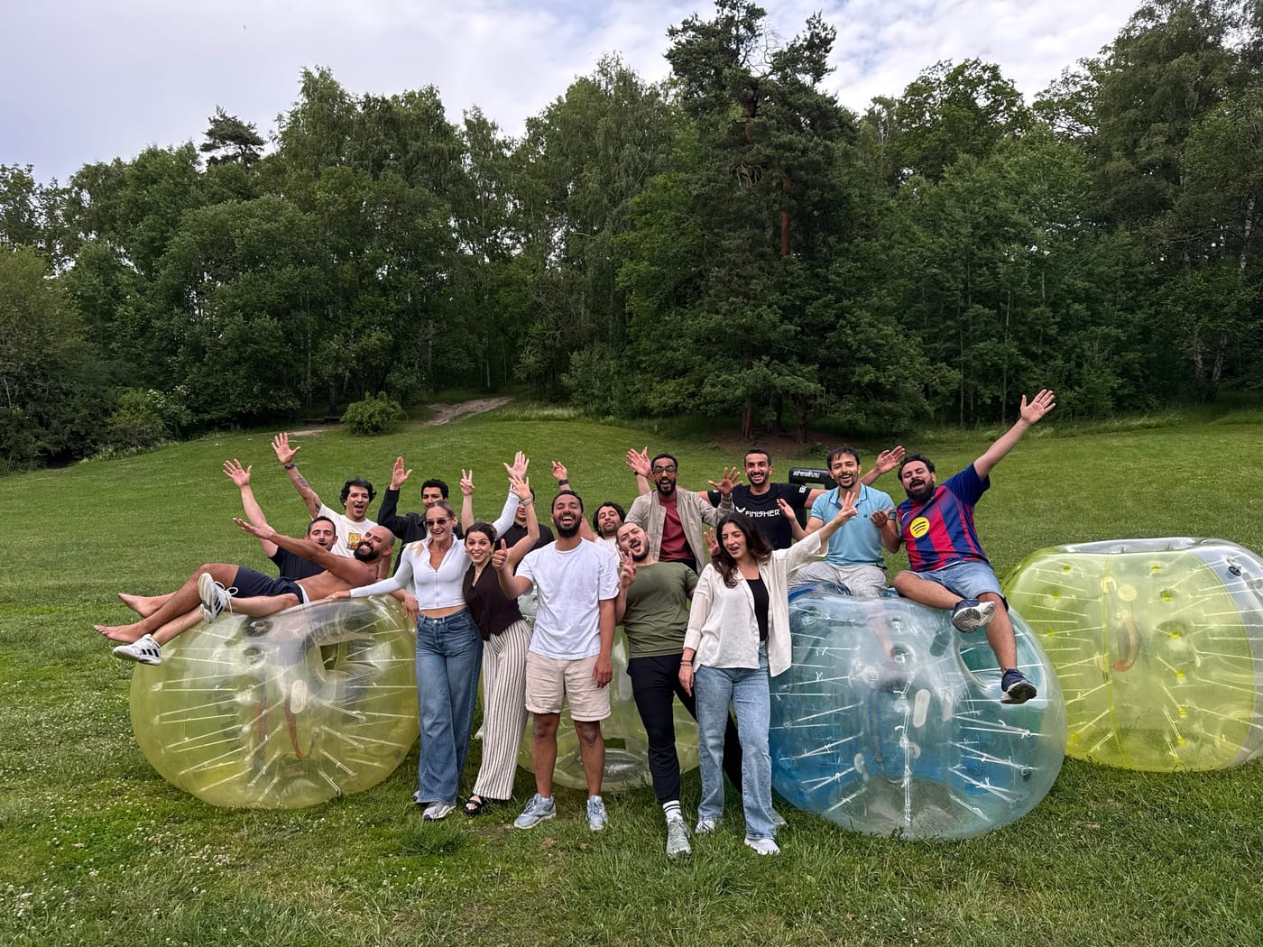SwedQ colleagues cheering with arms raised beside inflatable bubble balls on a grass field