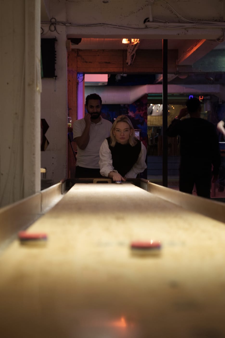 Colleague taking a shot at a shuffleboard table