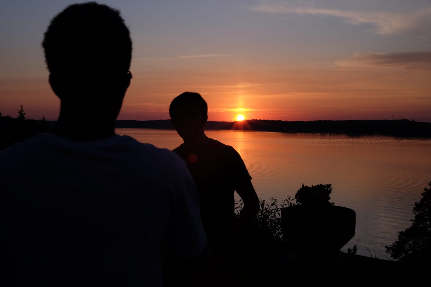 Two colleagues silhouetted against a sunset over the water